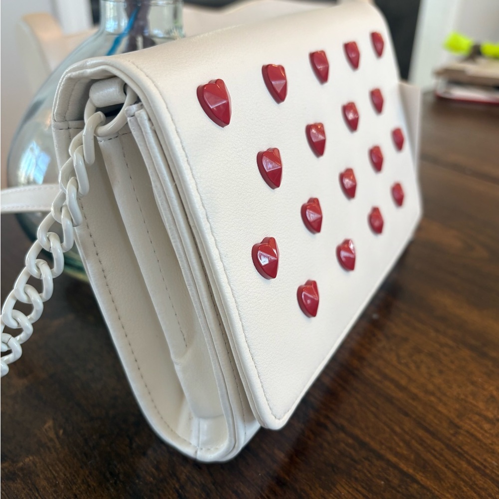 White crossbody purse with mini red hearts.